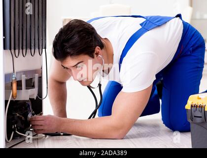 Repairman contractor repairing fridge in DIY concept Stock Photo