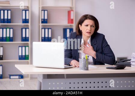 Middle-aged female employee suffering in the office Stock Photo