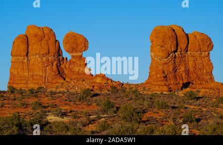 Unusually shaped sandstone column reach toward the sky in Arches National Park. People walking among the rocks give an idea of the columns size. Stock Photo