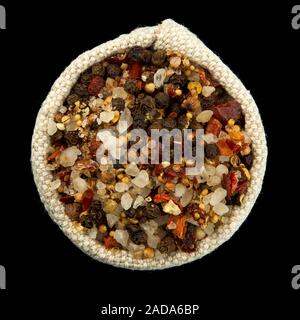 A mixture of peppers and salt in a bag isolated on a black background. View from above. Seasoning on isolate. Dry spices. Stock Photo