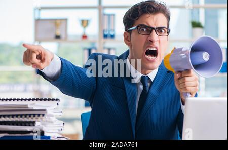 Angry aggressive Businessman with bullhorn loudspeaker in office Stock Photo