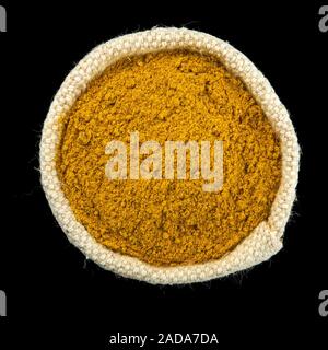 Turmeric powder in a bag isolated on a black background. View from above. Seasoning on isolate. Dry spices. Stock Photo