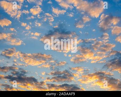 Beautiful golden clouds on sunset sky background. Blue sky background with golden light from sunlight shining on the clouds. Stock Photo