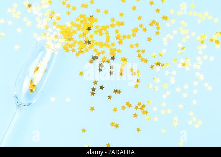 Champagne glass with sprinkles on blue background. Holiday, party and celebration concept. Horizontal Stock Photo