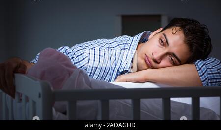 Young father dad sleeping while looking after newborn baby Stock Photo