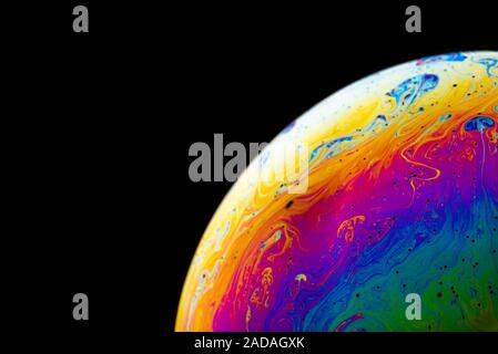 Rainbow soap bubble on a dark background. Stock Photo