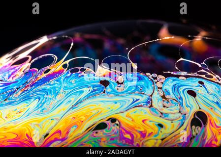 Rainbow soap bubble on a dark background. Stock Photo