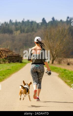 Girl running with Beagle dog outdoors in nature. Stock Photo