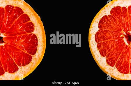 Fresh red grapefruit cut in half on black background. Stock Photo