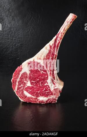 Raw dry aged wagyu tomahawk steak on black background with copy space Stock Photo