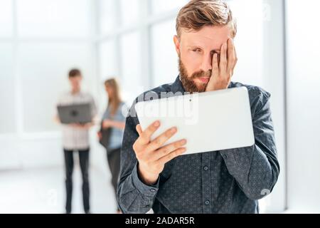 close up. frustrated man looking at the screen of his tablet. photo with copy space Stock Photo