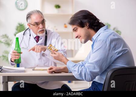 Young male alcoholic visiting old doctor Stock Photo