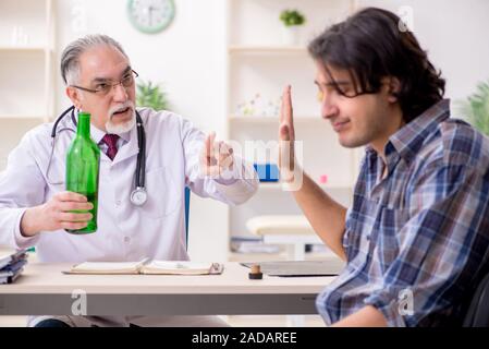 Young male alcoholic visiting old doctor Stock Photo