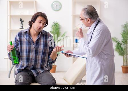 Young male alcoholic visiting old doctor Stock Photo