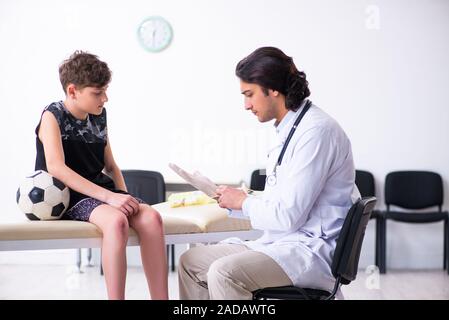 Boy football player visiting young doctor traumatologist Stock Photo