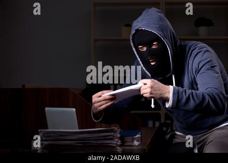 Male thief in balaclava in the office night time Stock Photo