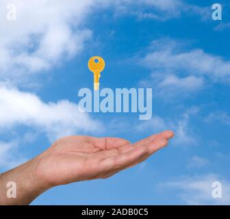 Close up of hand  and golden key on sky background Stock Photo
