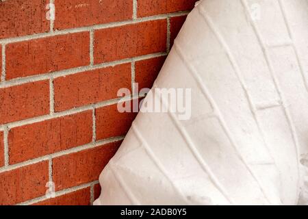 Sheet of snow peeling away from brick wall with an impression of the brick wall's texture. Golden, Colorado, USA Stock Photo