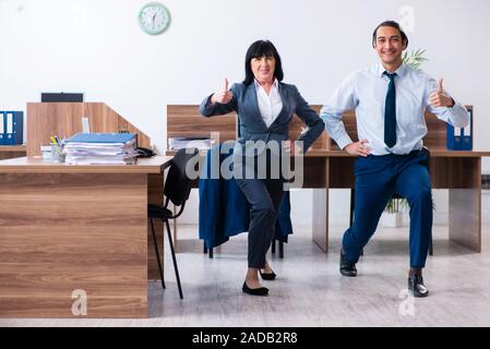 Two employees doing sport exercises in the office Stock Photo