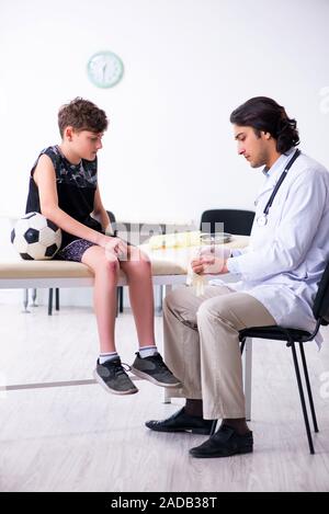 Boy football player visiting young doctor traumatologist Stock Photo