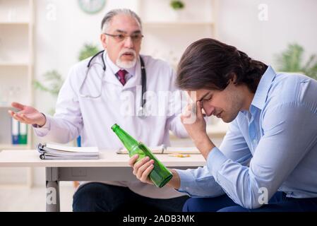 Young male alcoholic visiting old doctor Stock Photo