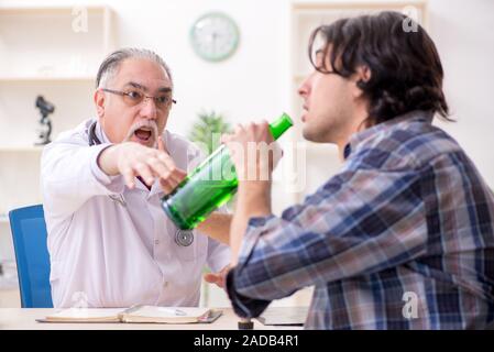 Young male alcoholic visiting old doctor Stock Photo