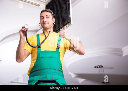 Young repairman repairing ceiling air conditioning unit Stock Photo