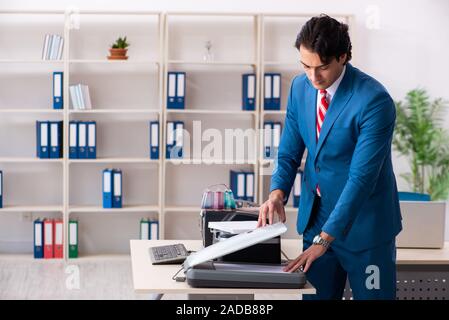 Young employee making copies at copying machine Stock Photo