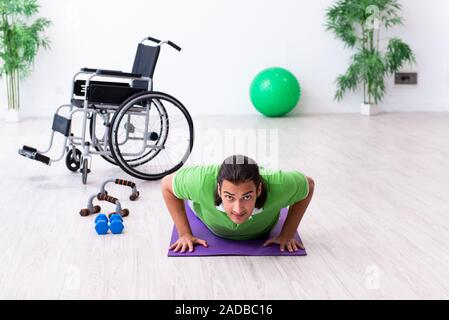 Young man in wheel-chair doing exercises indoors Stock Photo