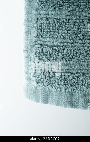 Green soft plush towel hanging from hanger background close up Stock Photo