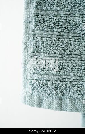 Green soft plush towel hanging from hanger background close up Stock Photo