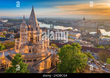 Budapest, Hungary - Beautiful golden summer sunrise with the tower of Fisherman's Bastion and green trees. Parliament of Hungary and River Danube at b Stock Photo