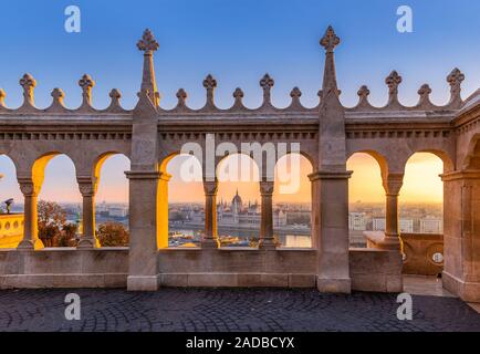 Budapest, Hungary - Beautiful warm autumn sunrise at Fisherman's Bastion with Parliament of Hungary at background. Clear blue sky and golden lights Stock Photo