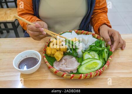 Woman eating Vietnamese fried tofu rice noodles and shrimp paste Stock Photo