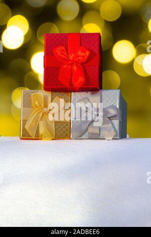 Colourful Gift boxes Presents on snow with christmas lights on the Background on a vertical view Stock Photo
