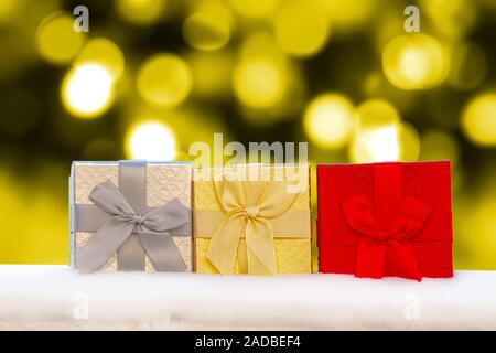 Colourful Gif boxes Presents on snow with golden christmas lights on the Background Stock Photo