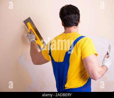 Young contractor employee applying plaster on wall Stock Photo