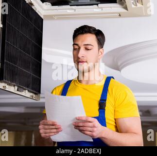 Repairman repairing ceiling air conditioning unit Stock Photo