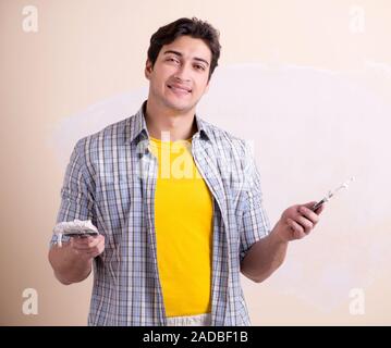 Young man applying plaster on wall at home Stock Photo