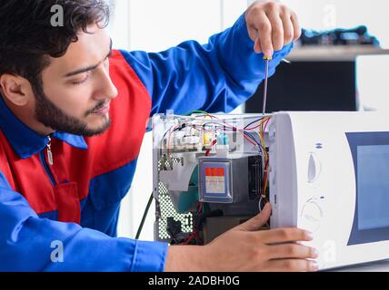 Young repairman fixing and repairing microwave oven Stock Photo