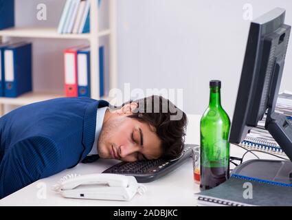 Young Businessman employee drinking in the office at desk Stock Photo