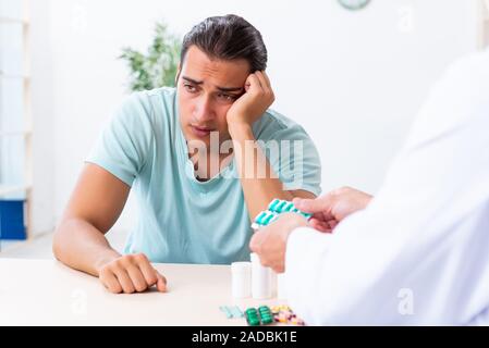 Young man visiting old male doctor Stock Photo