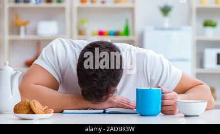 Man falling asleep during his breakfast after overtime work Stock Photo