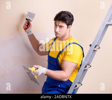 Young contractor employee applying plaster on wall Stock Photo