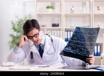 Young doctor looking at x-ray images in clinic Stock Photo