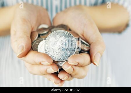 Bitcoin coin. Woman show her golden bitcoin on white background. Close-up. Stock Photo