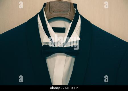stylish black suit with white shirt and bow tie on hanger . morning preparations before wedding day. groom outfit Stock Photo