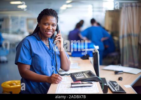 Hospital nurse at work. Nurse using a telephone on a hospital ward. Stock Photo