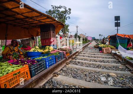 Vegetable market held on railway tracks, a woman is selling cauliflowers, aubergines and cucumbers Stock Photo