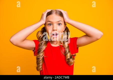 Photo of charming funny small lady school girl holding arms on head listen unbelievable good news wear casual red t-shirt isolated bright yellow color Stock Photo